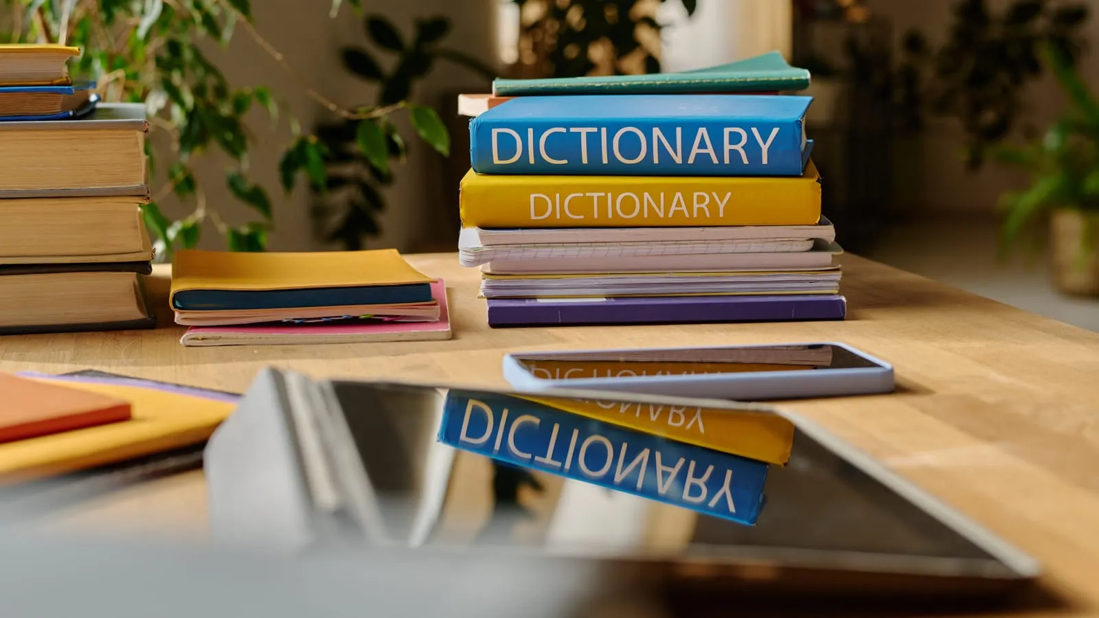 Stacks of colourful dictionaries and notebooks on a wooden table