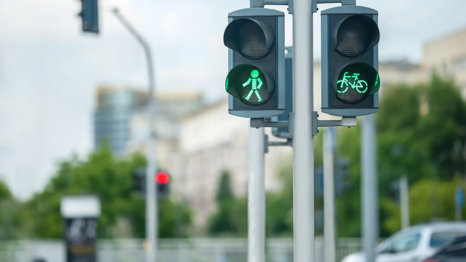 Pedestrian and cyclist traffic lights both showing green on a city street