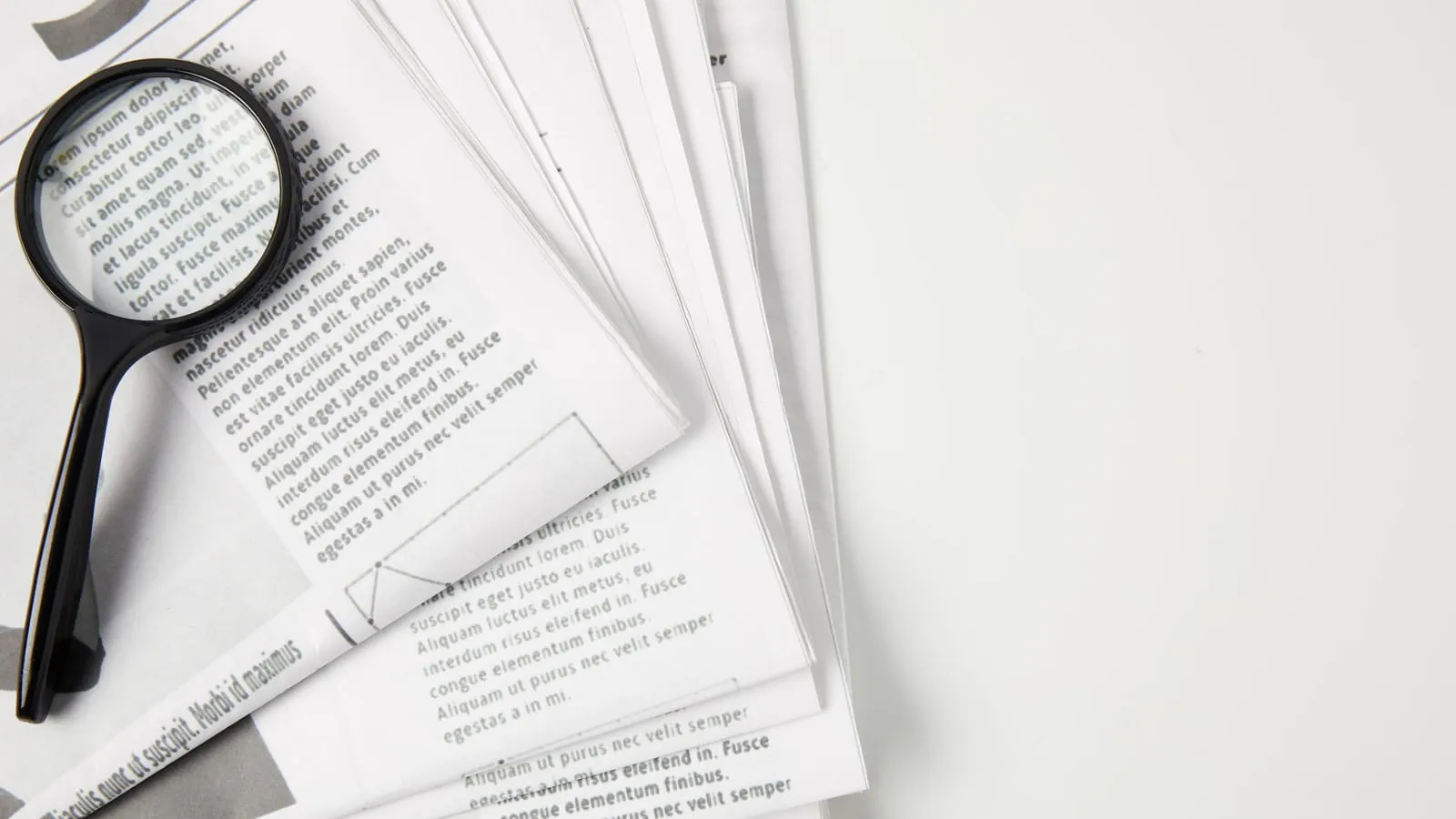 A magnifying glass resting on a pile of printed pages