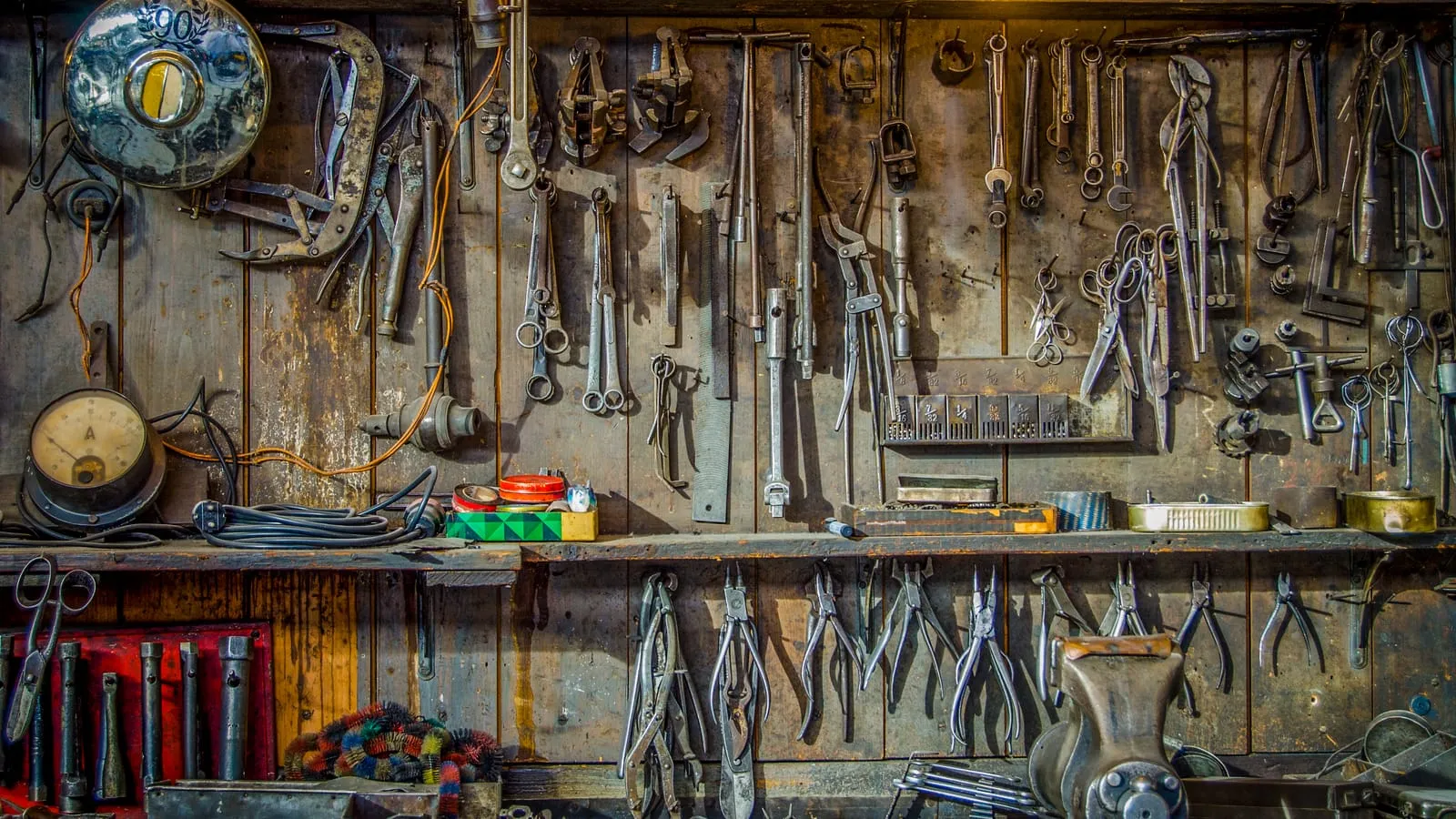 A workshop wall crowded with hanging hand tools above a workbench